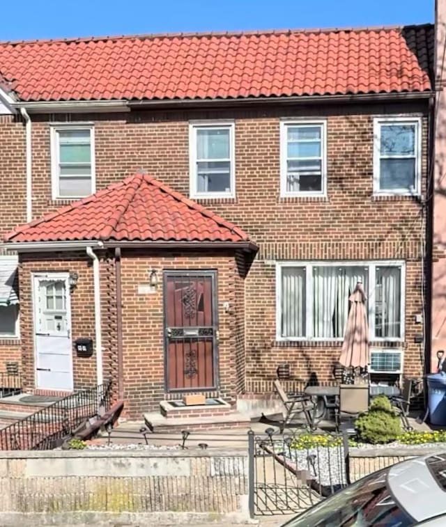 townhome / multi-family property featuring brick siding and a tiled roof