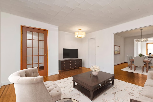 living room featuring a notable chandelier, baseboards, and wood finished floors