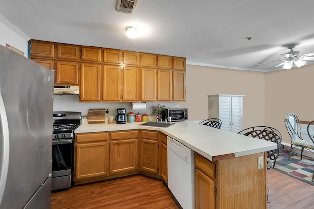 kitchen featuring under cabinet range hood, a peninsula, wood finished floors, visible vents, and appliances with stainless steel finishes