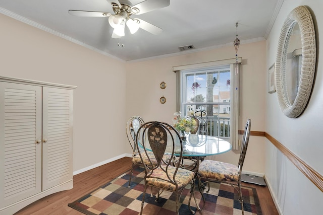 dining room with ceiling fan, wood finished floors, visible vents, baseboards, and ornamental molding