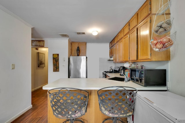 kitchen featuring stainless steel appliances, a peninsula, a sink, visible vents, and light countertops