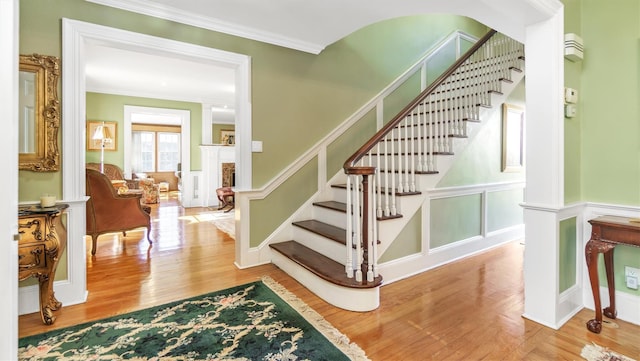 stairway featuring crown molding, a decorative wall, and wood finished floors