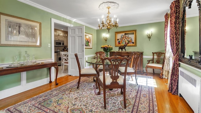 dining room with ornamental molding, radiator, an inviting chandelier, and wood finished floors