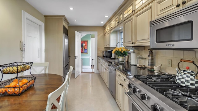 kitchen with stainless steel appliances, dark countertops, recessed lighting, backsplash, and cream cabinets