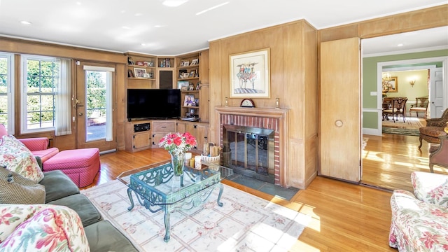 living room with ornamental molding, a brick fireplace, and light wood-style flooring