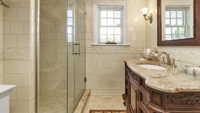 bathroom featuring plenty of natural light, a shower stall, tile walls, and vanity