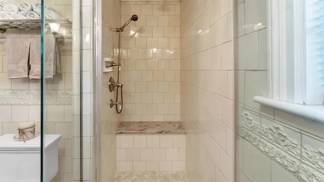 bathroom with toilet, a stall shower, and tile walls