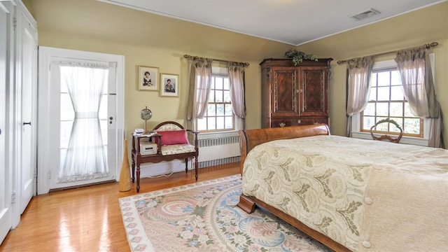 bedroom featuring light wood finished floors, visible vents, and radiator