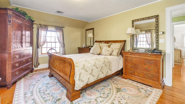 bedroom featuring light wood-type flooring, multiple windows, visible vents, and lofted ceiling