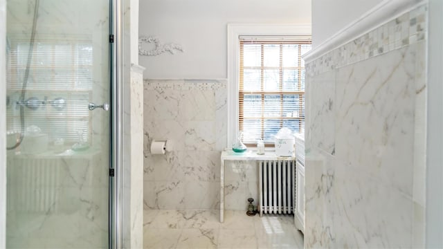 bathroom with marble finish floor, a marble finish shower, tile walls, and radiator