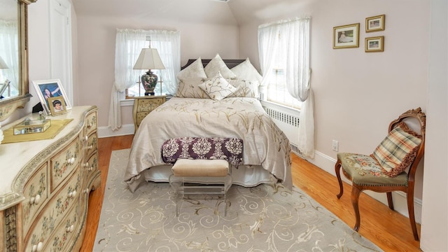 bedroom featuring baseboards, wood finished floors, and radiator