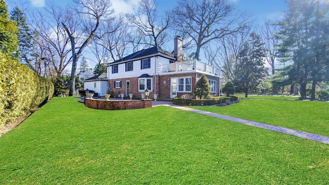 rear view of house with a patio, a balcony, brick siding, a lawn, and a chimney