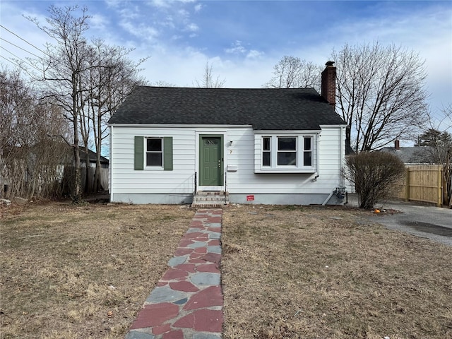 bungalow featuring entry steps, a chimney, roof with shingles, fence, and a front yard