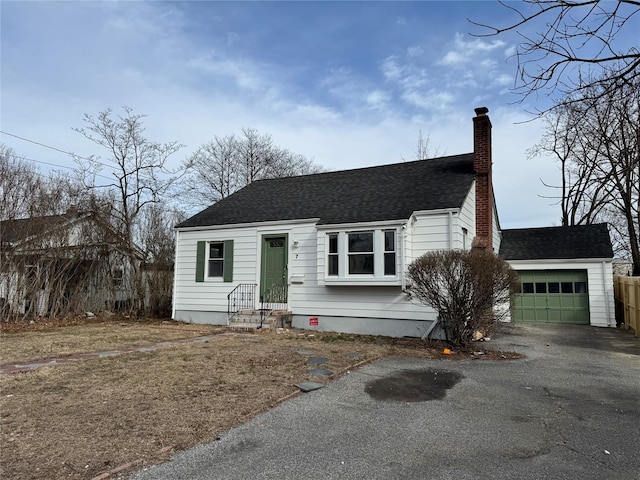 view of front of property with roof with shingles, aphalt driveway, a chimney, and an attached garage