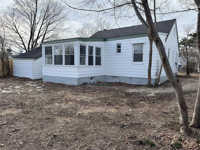 view of side of home with a shingled roof and crawl space