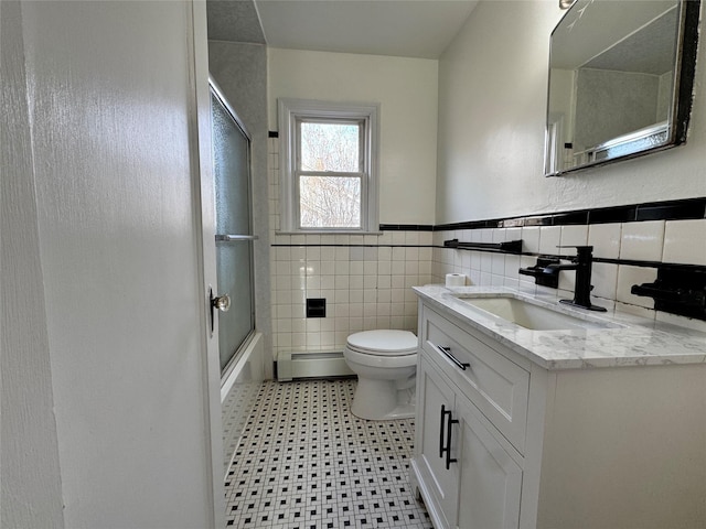 bathroom with enclosed tub / shower combo, toilet, vanity, tile walls, and baseboard heating