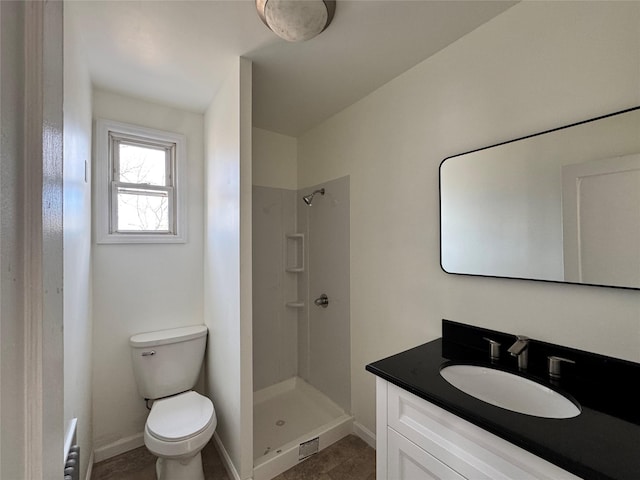 bathroom with toilet, a stall shower, baseboards, and vanity