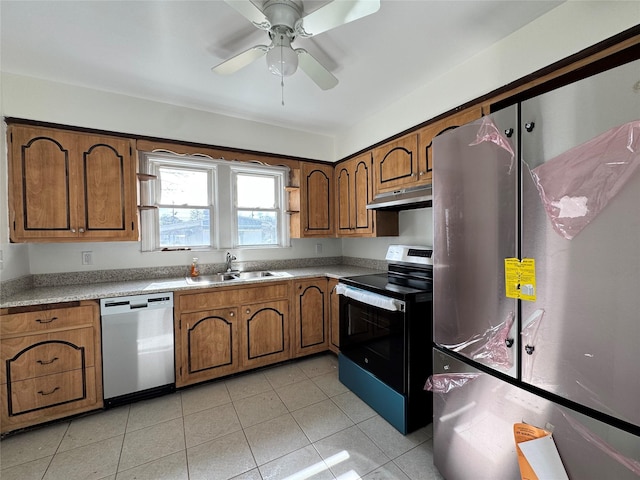 kitchen with brown cabinets, stainless steel appliances, light countertops, a sink, and under cabinet range hood