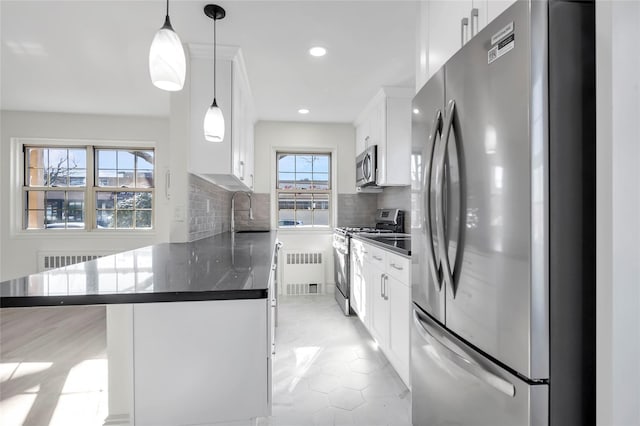 kitchen featuring white cabinets, pendant lighting, stainless steel appliances, and backsplash