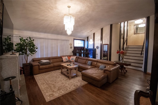 living room featuring lofted ceiling, an inviting chandelier, stairs, and wood finished floors