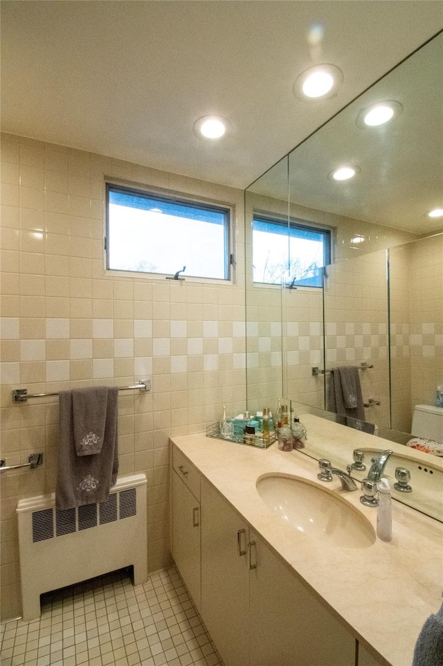 bathroom with radiator, tile patterned floors, vanity, tile walls, and recessed lighting