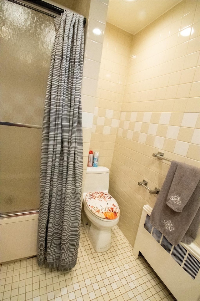 bathroom with shower / tub combo, radiator, toilet, tile patterned floors, and tile walls