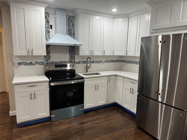 kitchen featuring light countertops, appliances with stainless steel finishes, dark wood-type flooring, a sink, and wall chimney exhaust hood