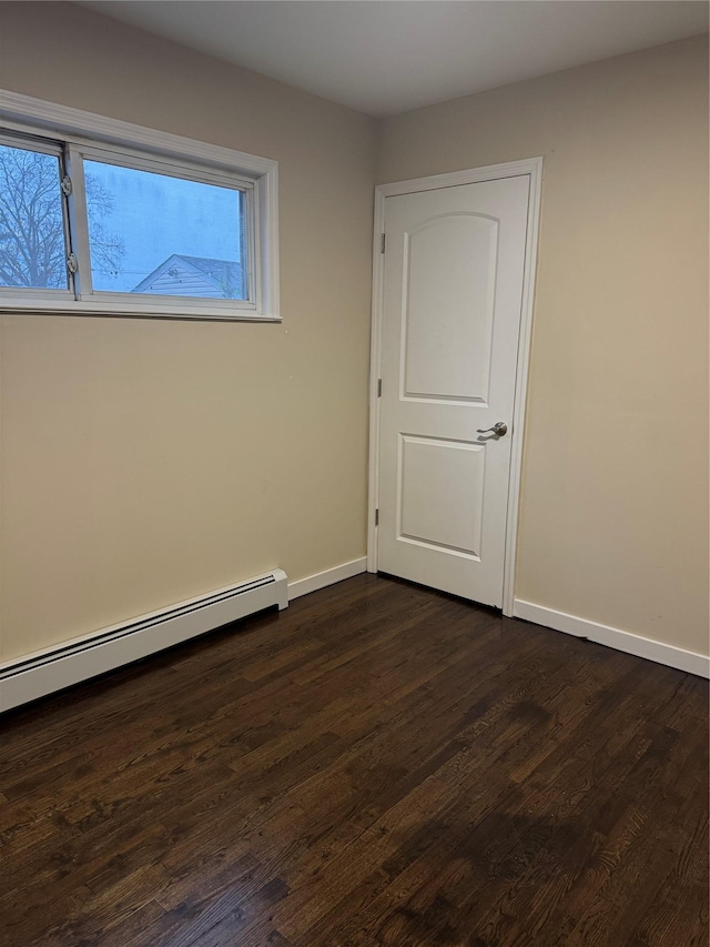 unfurnished room featuring dark wood-type flooring, baseboards, and baseboard heating