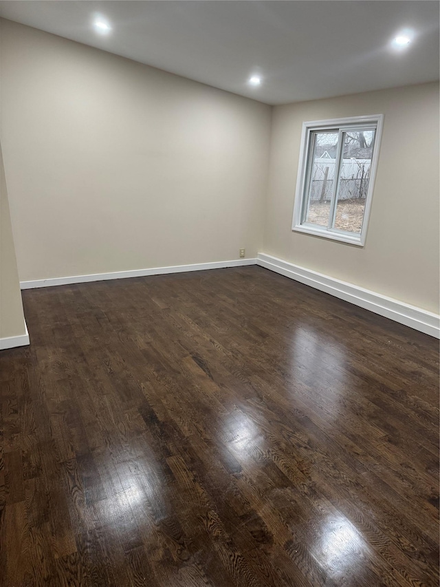 empty room with recessed lighting, dark wood-style flooring, and baseboards