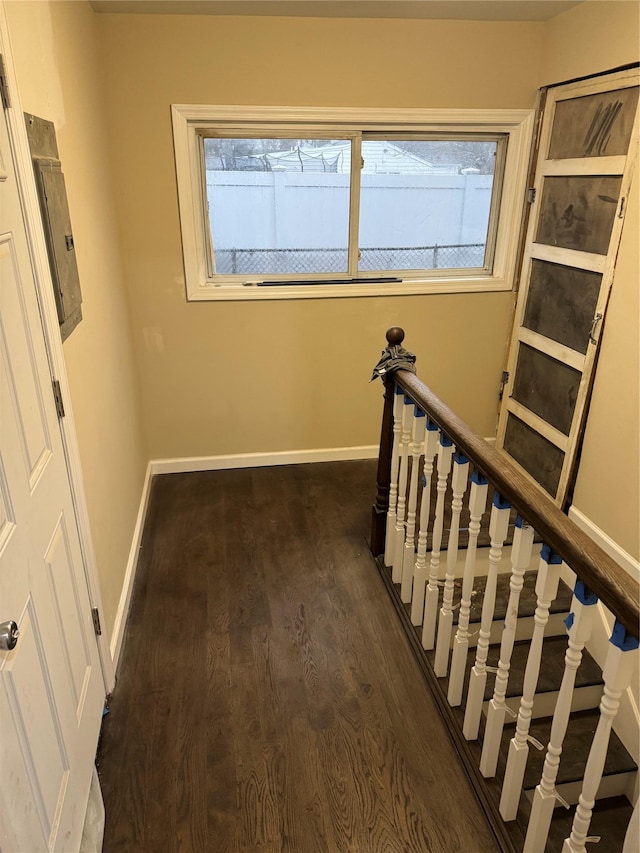 hallway with dark wood-style floors, a healthy amount of sunlight, an upstairs landing, and baseboards