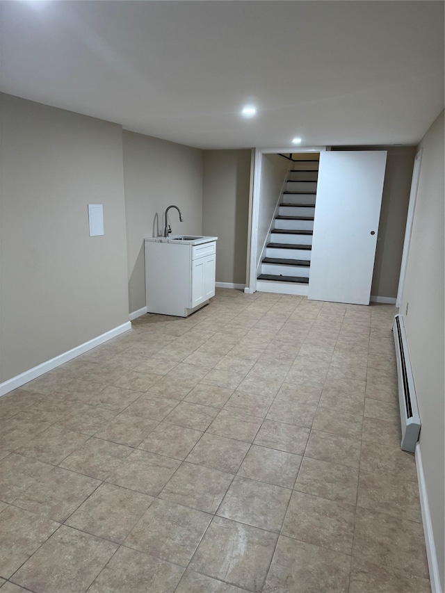 finished below grade area featuring baseboards, stairs, a baseboard heating unit, a sink, and recessed lighting