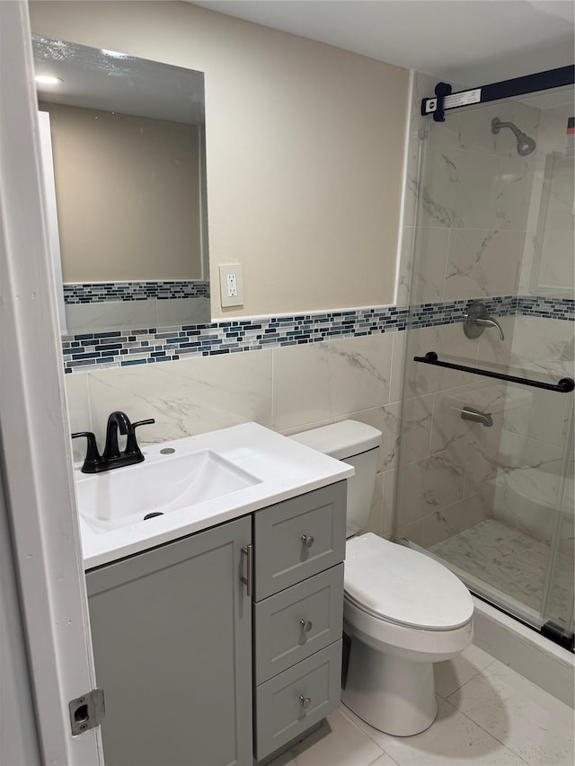 bathroom featuring toilet, a shower stall, tile walls, and vanity