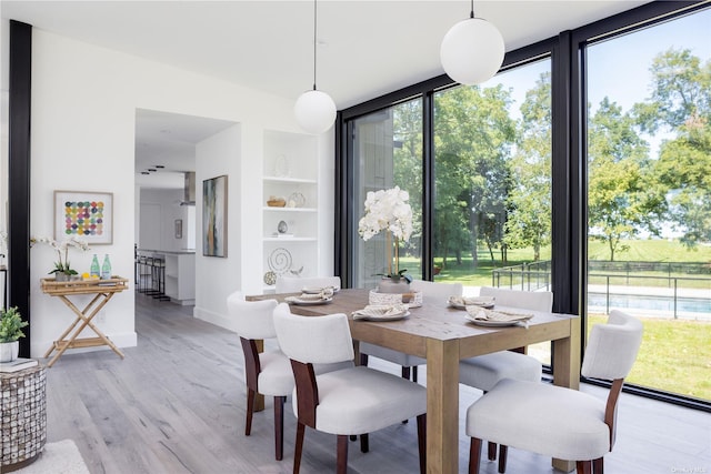 dining space with floor to ceiling windows and light wood-style floors