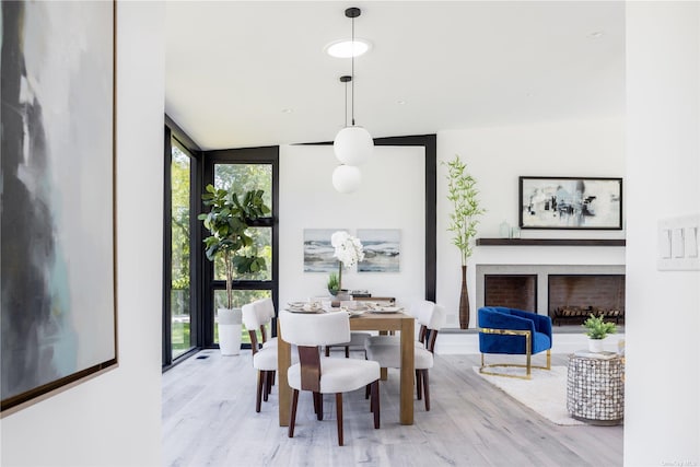 dining room with expansive windows, light wood finished floors, and a fireplace