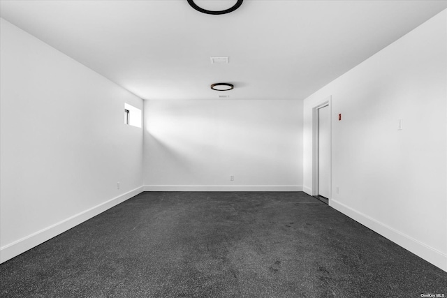 unfurnished room with baseboards and dark colored carpet