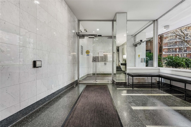 bathroom with a stall shower and tile walls