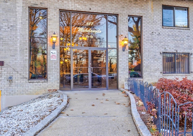 entrance to property featuring brick siding, fence, and french doors