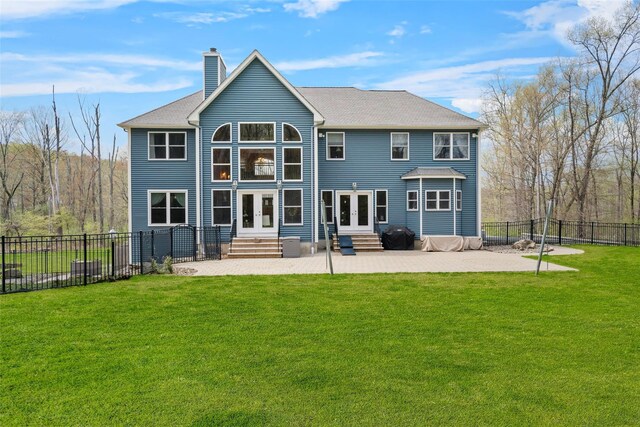 back of property with entry steps, a chimney, a yard, and french doors