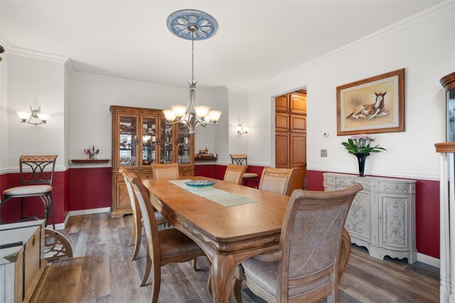 dining area with ornamental molding, wood finished floors, and a notable chandelier