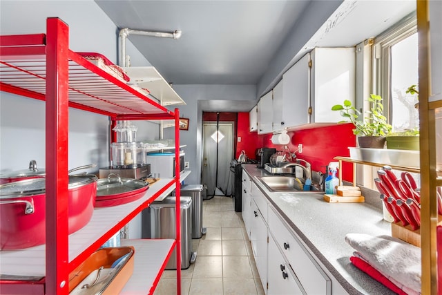 kitchen featuring range, white cabinets, a sink, and light tile patterned floors