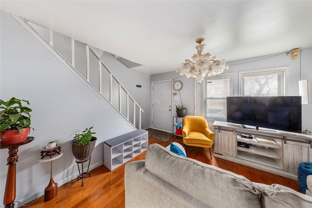 living area featuring stairs, wood finished floors, and a notable chandelier