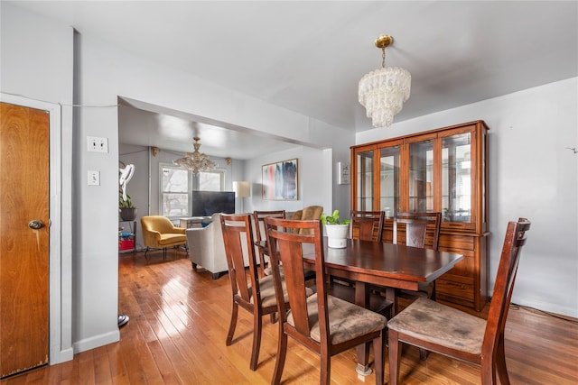 dining space with baseboards, hardwood / wood-style flooring, and a notable chandelier