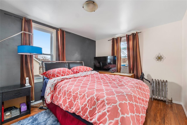 bedroom with radiator heating unit, wood finished floors, and baseboards