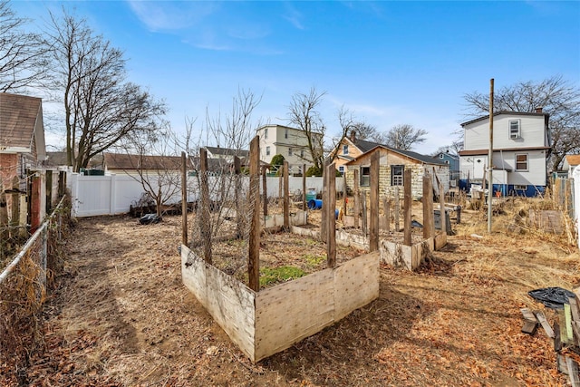 view of yard featuring a garden, a residential view, a fenced backyard, and an outdoor structure