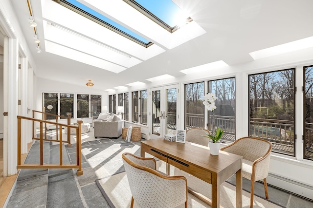 sunroom featuring a baseboard radiator and vaulted ceiling with skylight