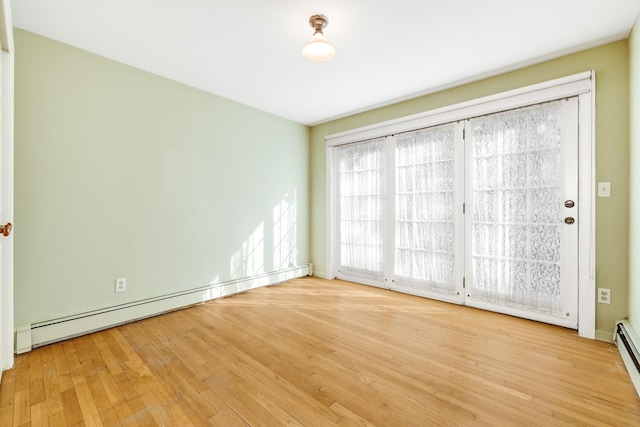 unfurnished room with a baseboard heating unit and wood finished floors