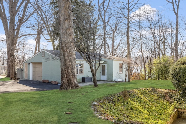 view of yard with a garage, cooling unit, and driveway