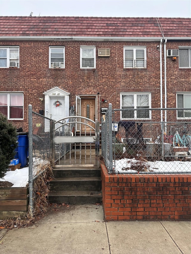 back of property featuring brick siding, a fenced front yard, and a gate