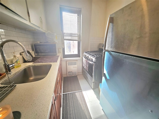 kitchen with tasteful backsplash, appliances with stainless steel finishes, a sink, and radiator