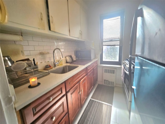 kitchen featuring visible vents, brown cabinetry, freestanding refrigerator, light countertops, and a sink